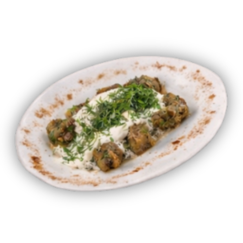 Lėkštėje patiektas patiekalas su smulkiais apvaliais gabalėliais, baltu kreminiu padažu ir smulkintomis