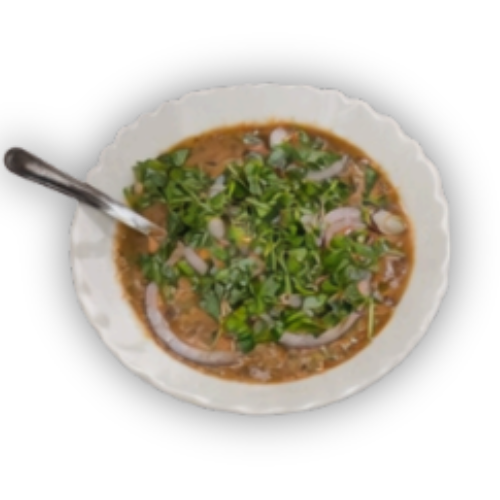 Keraminiame baltame dubenyje esantis rudos spalvos patiekalas su žalumynų ir raudonojo svogūno