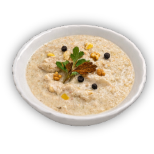 Balto keramikinio dubenėlio viduje kreminis smėlinės spalvos mišinys su gabalėliais, papuoštas petražolių