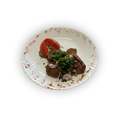 Balta keramikinė lėkštė su dekoratyviai išdėstytais rudos mėsos gabalėliais, kapotomis žolelėmis